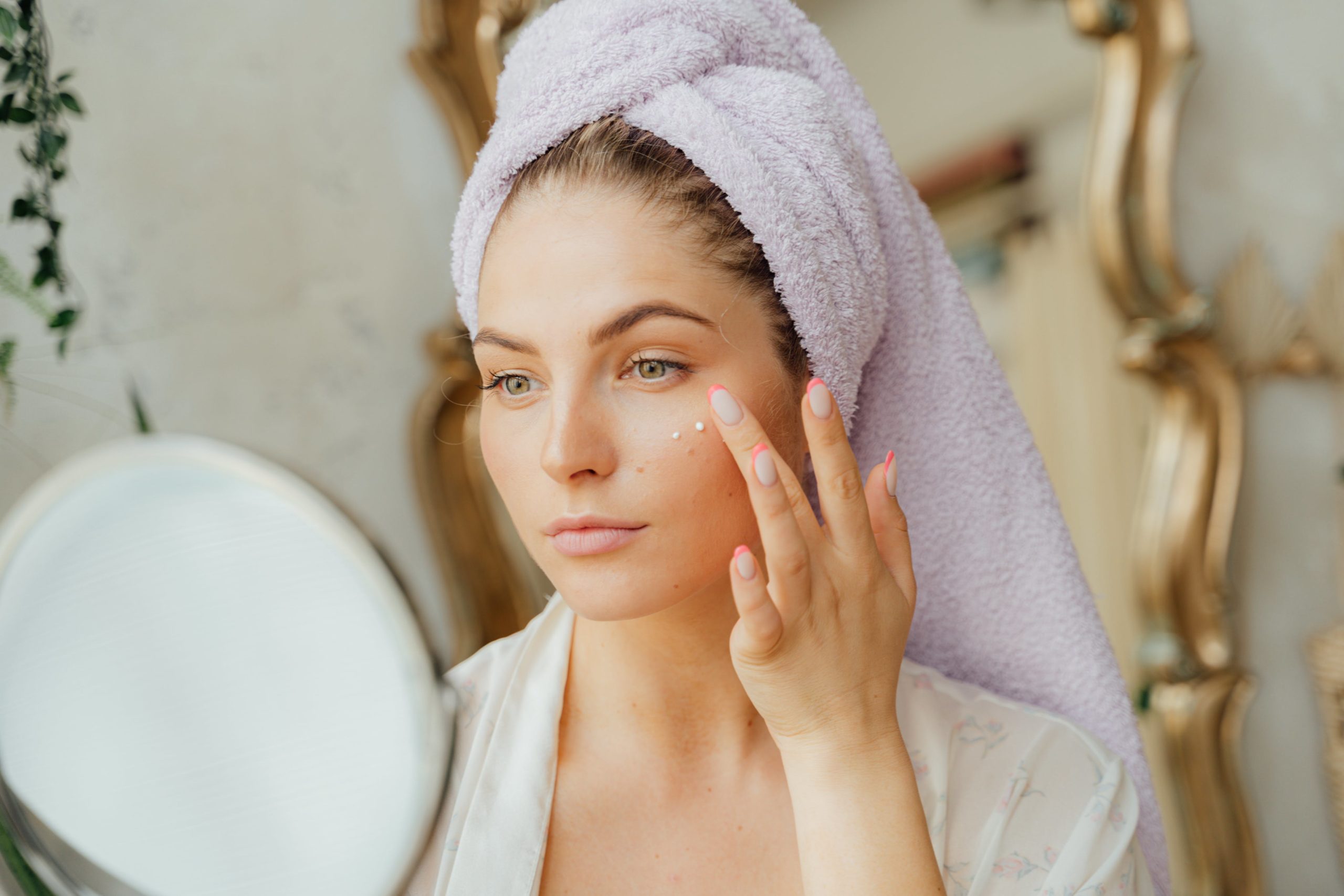 Woman applying spf after getting out of the shower to protect her skin from sun damage and aging