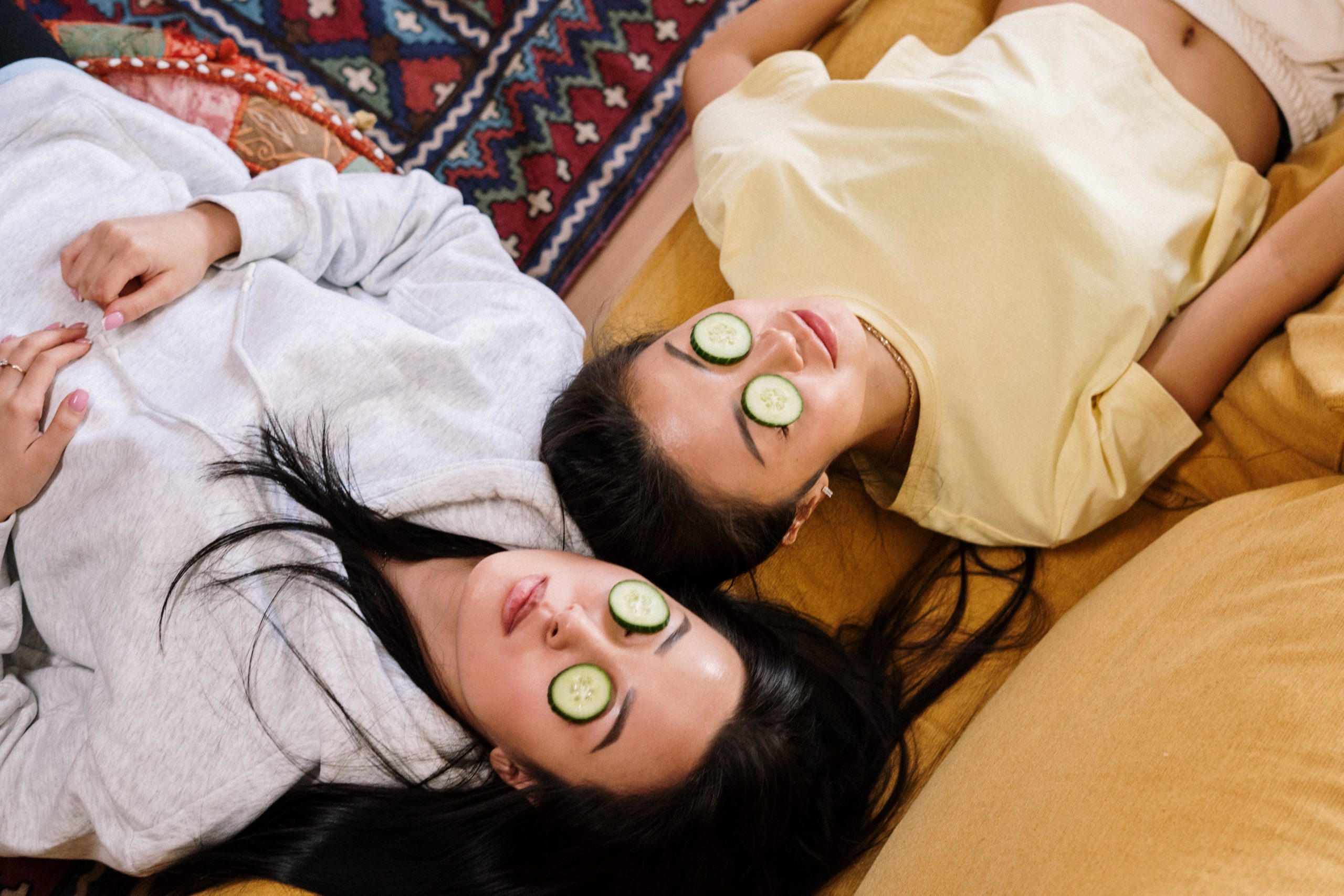 Two women having a skincare routine relaxing day at home, using cucumbers to cover their eyes to get rid of puffiness