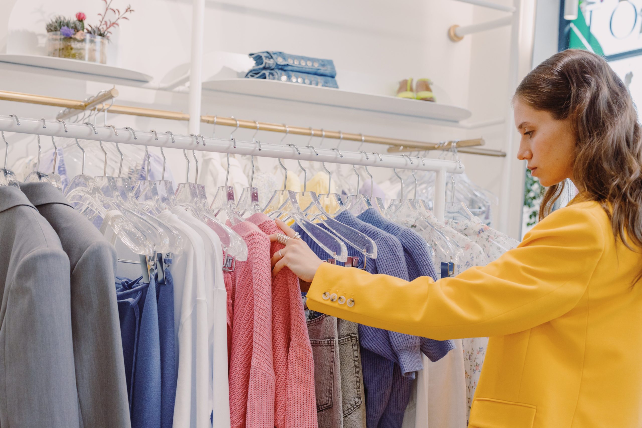 Woman browsing through clothing rack picking clothing items for capsule wardrobe