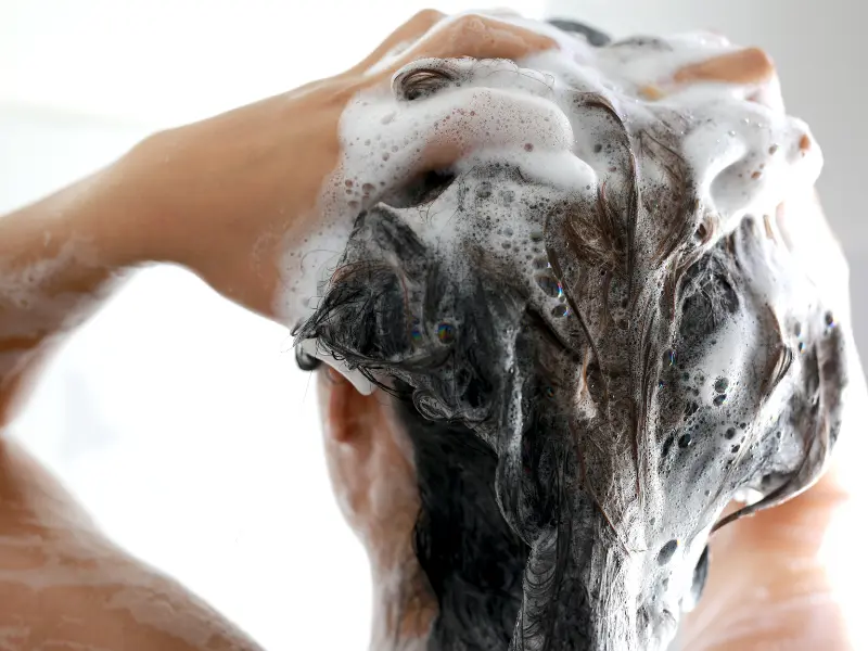 Woman in the shower washing her hair with shampoo