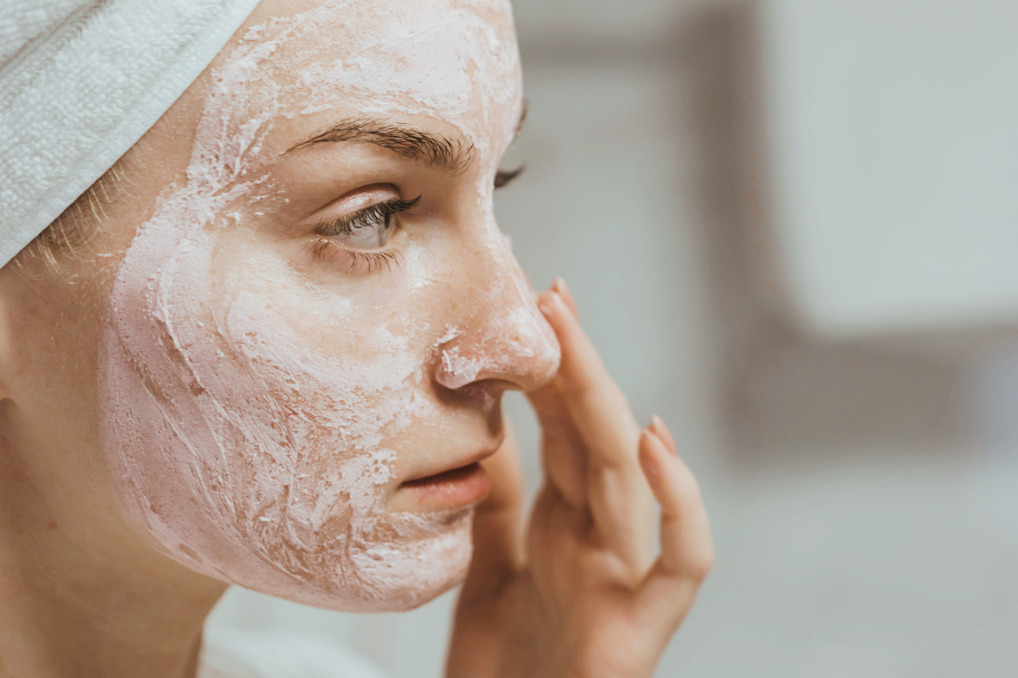 a woman using a physical exfoliant mask on her face