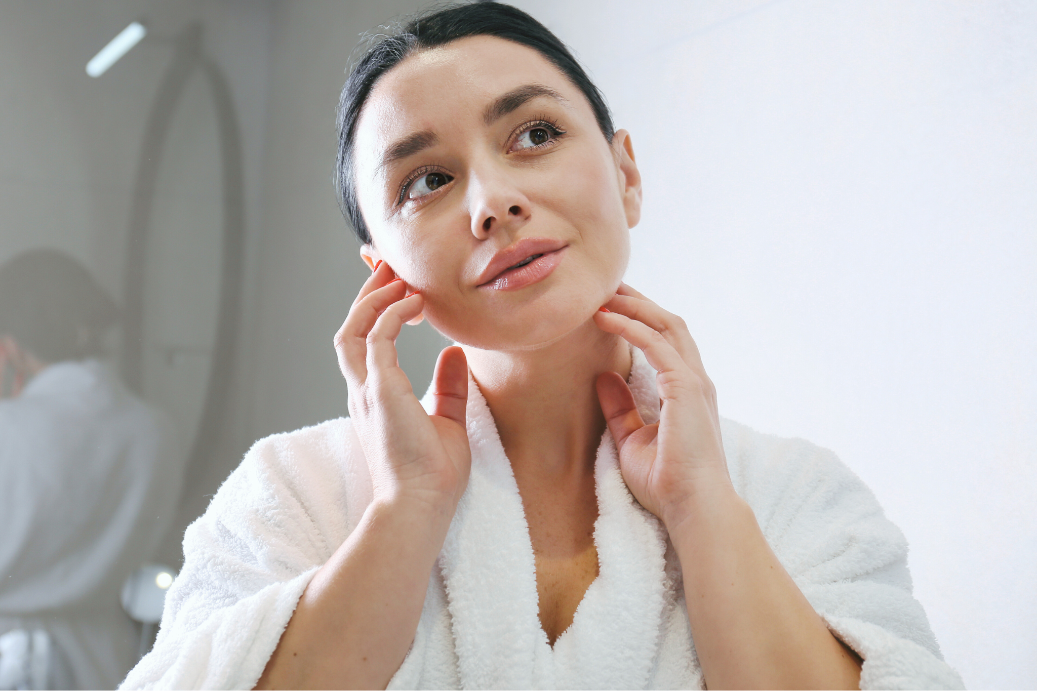 woman applying chemical exfoliant to her face while looking in the mirror